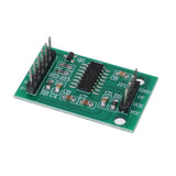 Tilted close-up of green HX711 amplifier module with circuit components for Arduino